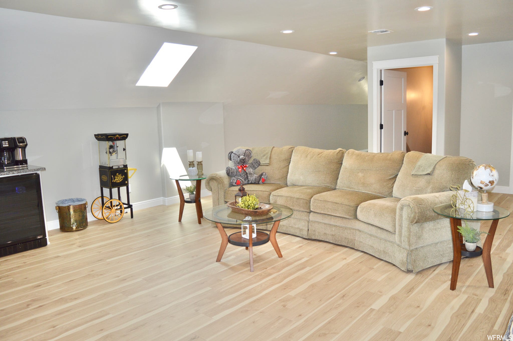 Hardwood floored living room with vaulted ceiling with skylight