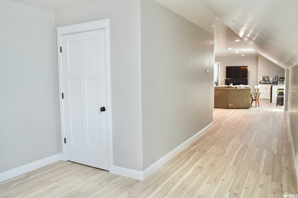Hallway featuring light parquet floors and vaulted ceiling