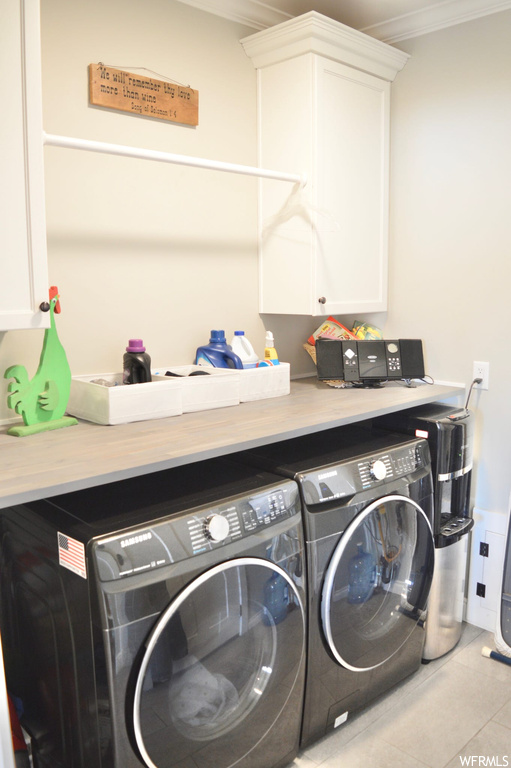 Laundry room with crown molding, separate washer and dryer, and light tile flooring