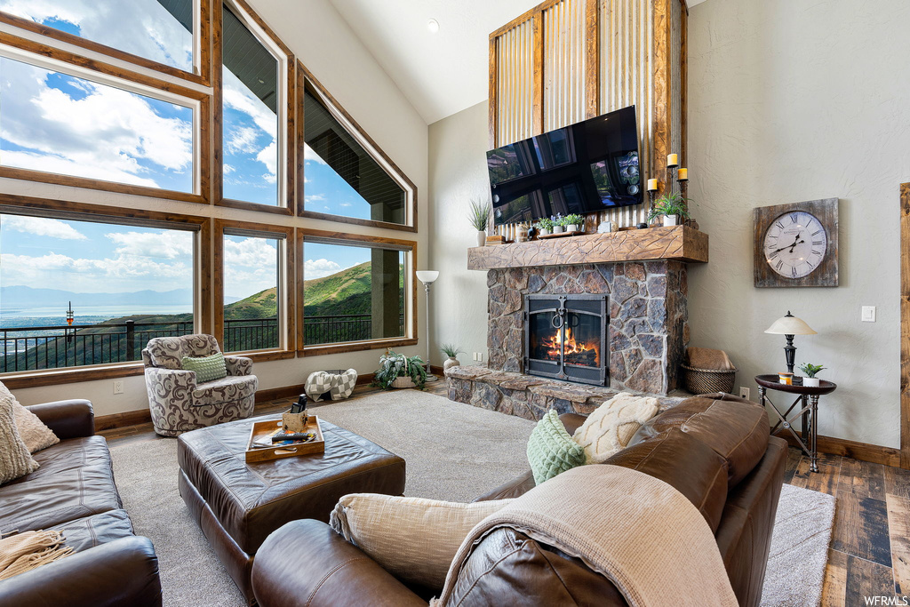 Hardwood floored living room featuring a fireplace, vaulted ceiling, and a high ceiling