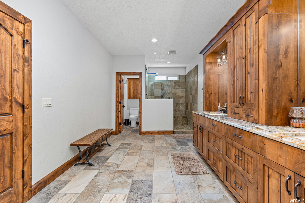 Bathroom with a shower with shower door, a textured ceiling, light tile floors, vanity, and mirror
