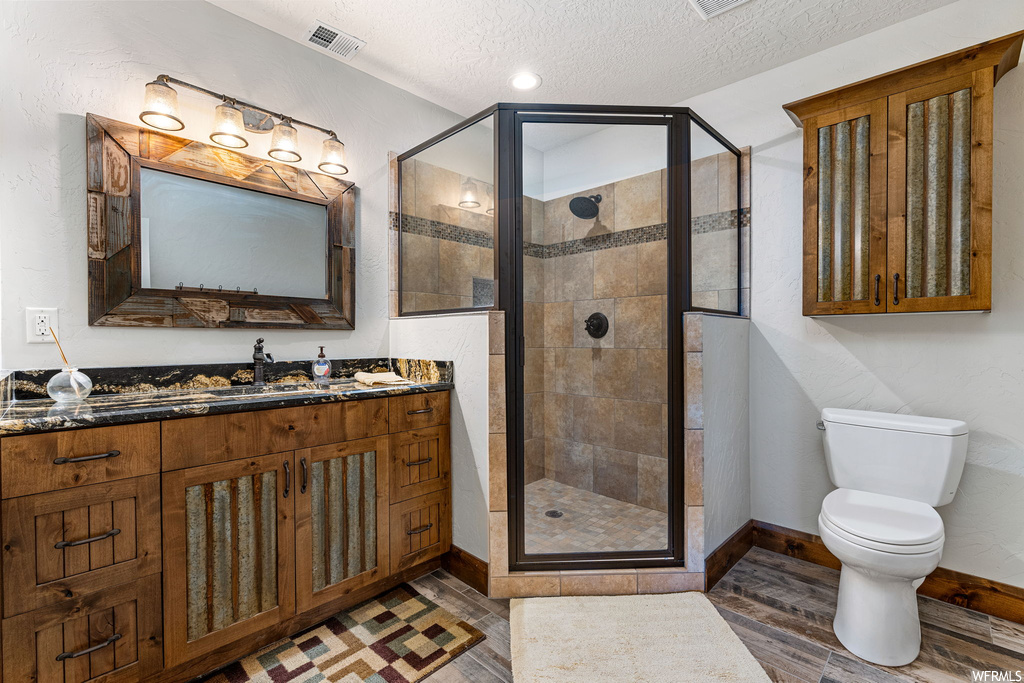 Bathroom with a shower with door, a textured ceiling, vanity, and mirror
