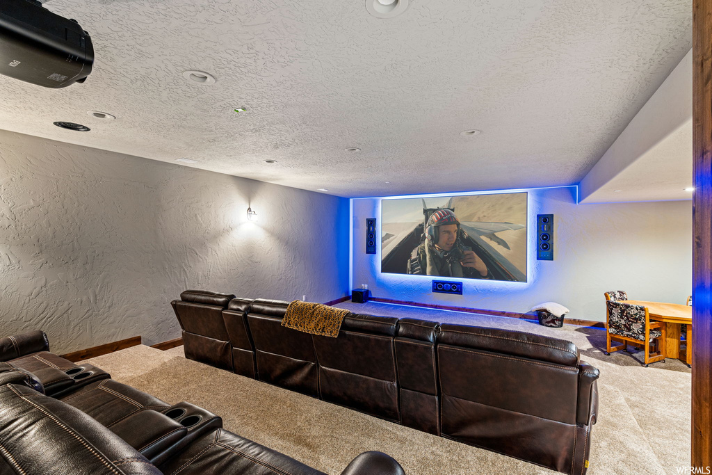 Carpeted home theater featuring a textured ceiling