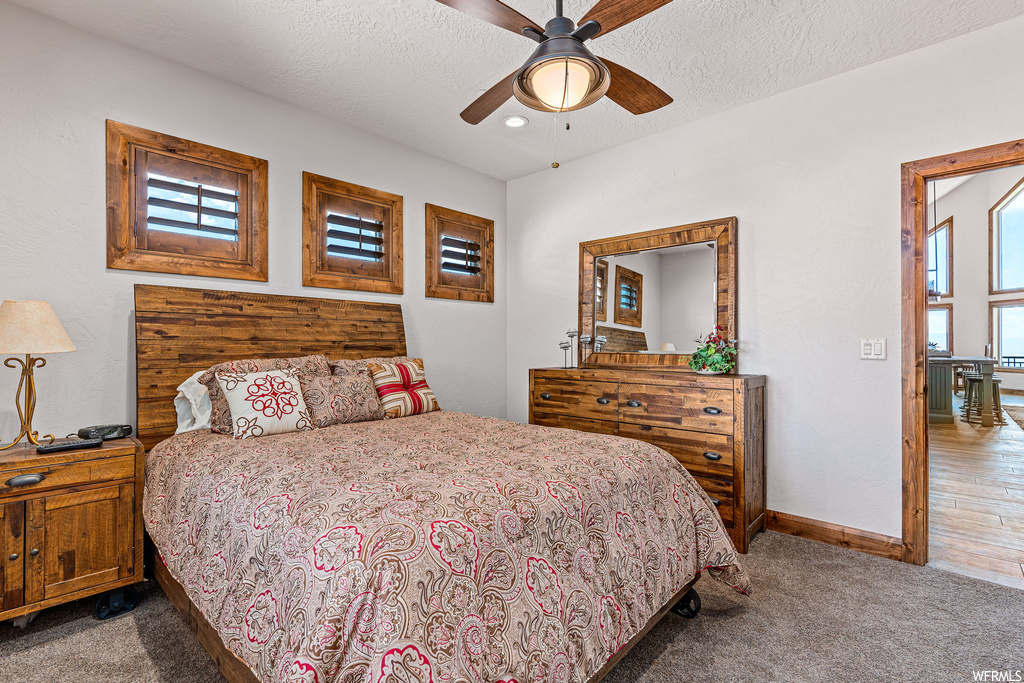 Carpeted bedroom featuring a textured ceiling and ceiling fan
