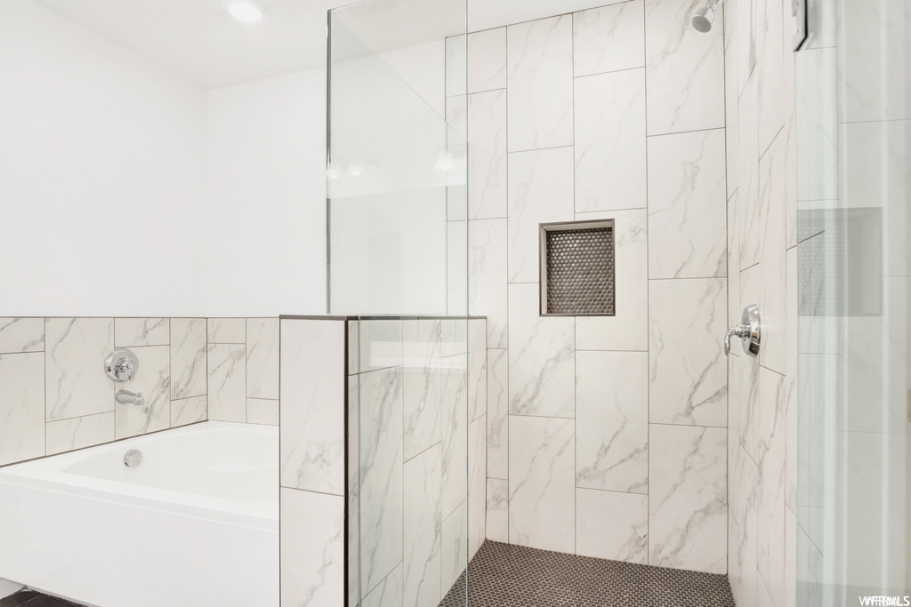 Bathroom featuring tile walls and separate shower and tub