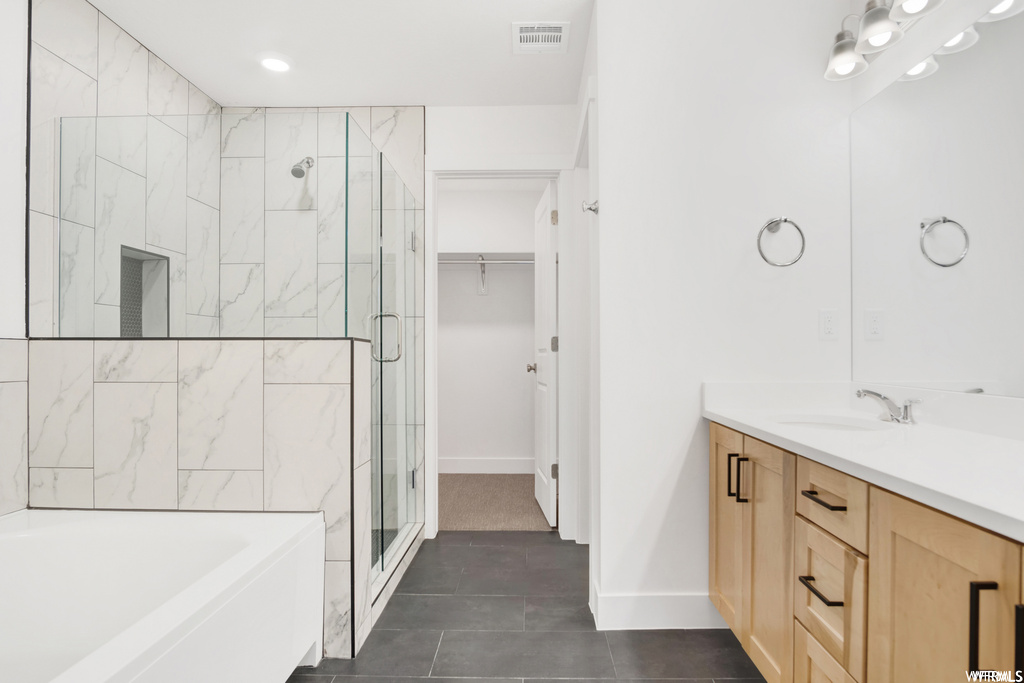Bathroom with separate shower and tub, vanity, dark tile floors, and mirror