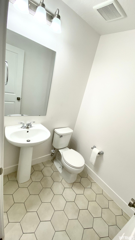 Bathroom featuring washbasin, mirror, and light tile floors