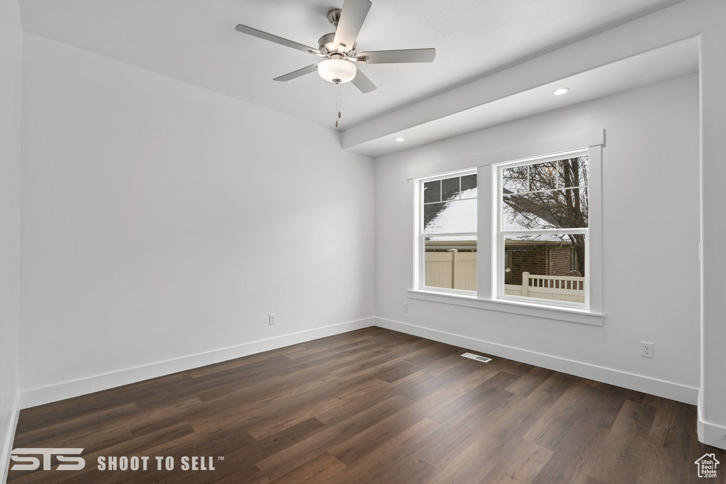 Empty room with dark wood-type flooring and ceiling fan