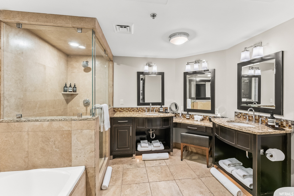 Bathroom with independent shower and bath, light tile floors, double sink vanity, and mirror