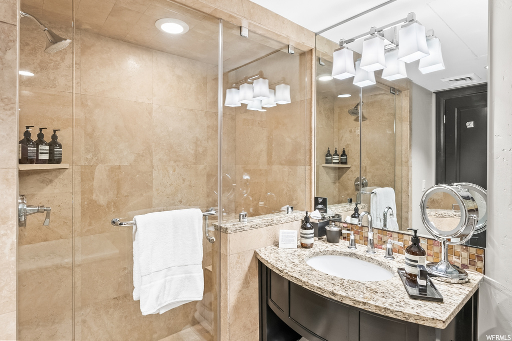 Bathroom with tile walls, large vanity, a shower with door, backsplash, and mirror