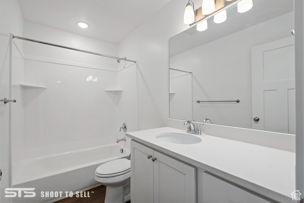 Full bathroom featuring hardwood / wood-style flooring, toilet,  shower combination, and oversized vanity