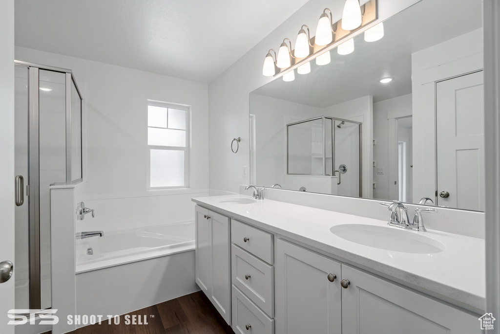 Bathroom featuring dual sinks, large vanity, plus walk in shower, and hardwood / wood-style flooring