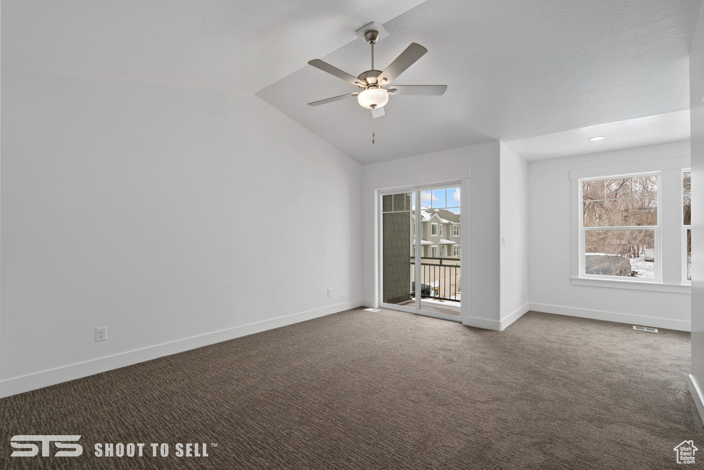 Unfurnished room with vaulted ceiling, dark colored carpet, and ceiling fan