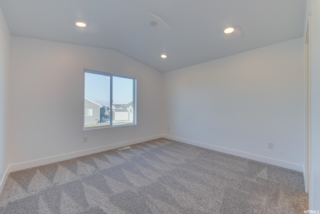 Unfurnished room with lofted ceiling and carpet flooring