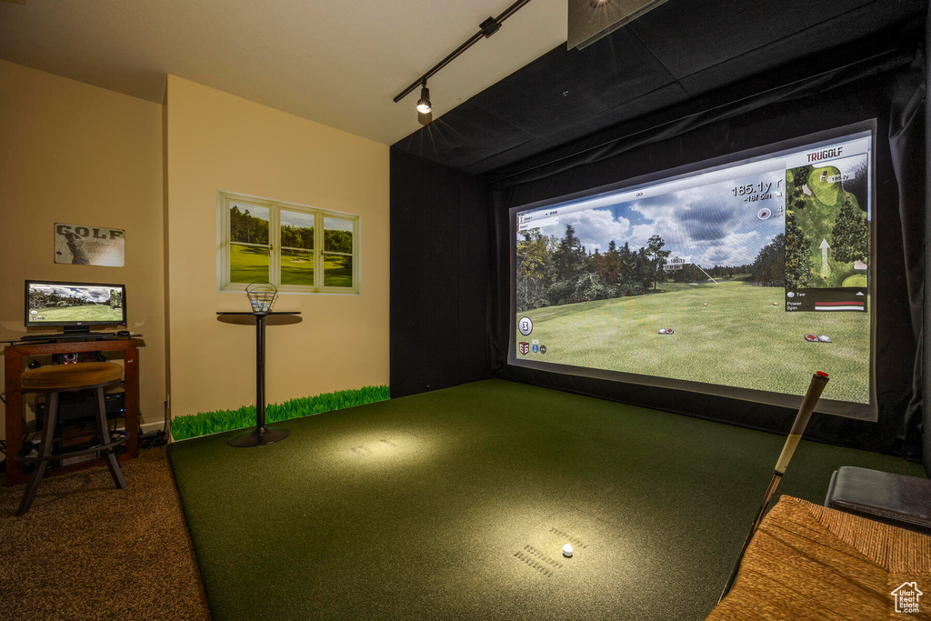 Recreation room featuring dark carpet, golf simulator, and track lighting