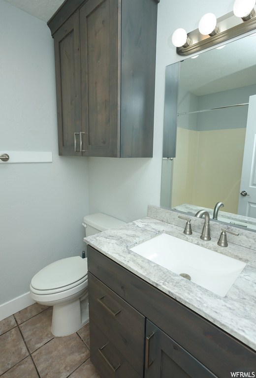 Bathroom featuring vanity with extensive cabinet space, mirror, and tile flooring