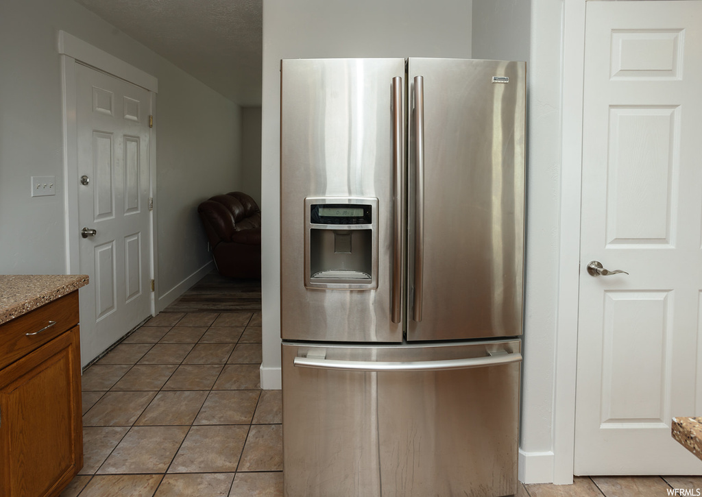 Kitchen with light tile floors and stainless steel fridge with ice dispenser