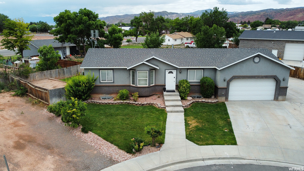 View of front of house with garage, a front yard, and a mountain view