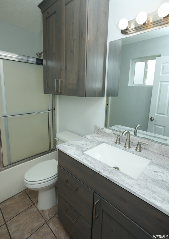 Full bathroom with combined bath / shower with glass door, vanity, tile floors, and mirror