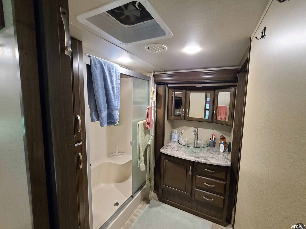 Bathroom with an enclosed shower, vanity with extensive cabinet space, tile floors, and mirror
