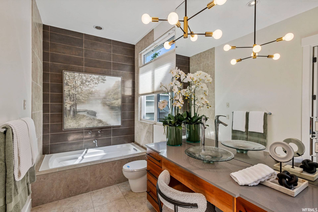 Bathroom featuring light tile flooring, mirror, vanity, tiled tub, and tile walls