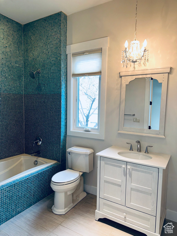 Full bathroom featuring vanity, toilet, an inviting chandelier, and tiled shower / bath