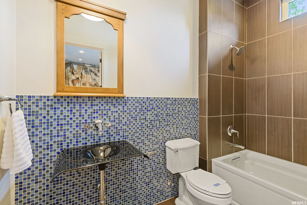 Full bathroom featuring tile walls, sink, tiled shower / bath, and mirror