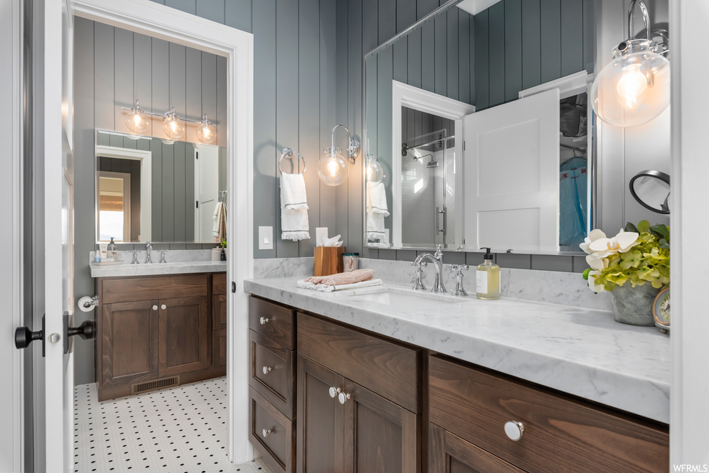 Bathroom featuring dual vanity, mirror, and tile flooring