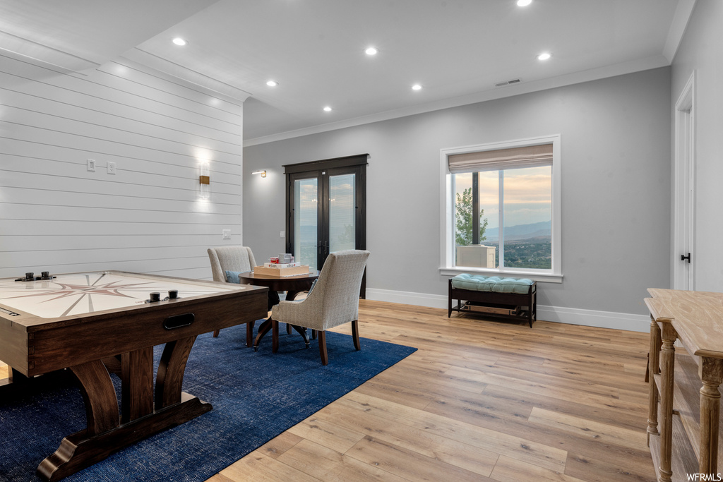 Game room with crown molding and light hardwood flooring