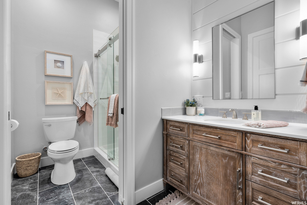 Bathroom featuring tile flooring, vanity, mirror, and a shower with door