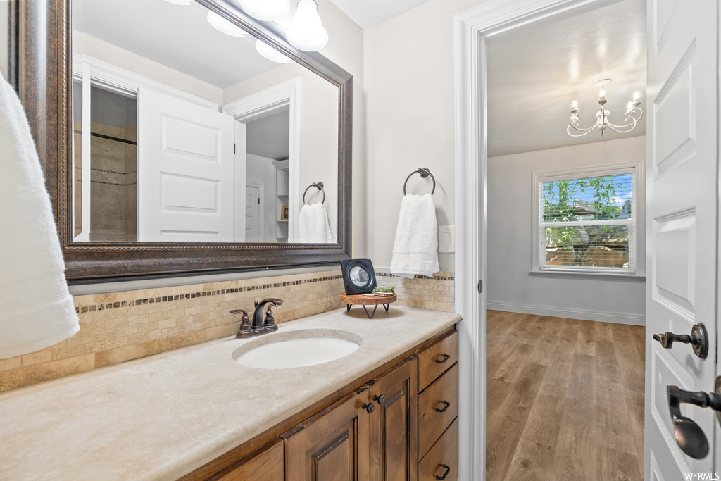 Bathroom with backsplash, vanity, light hardwood flooring, and mirror