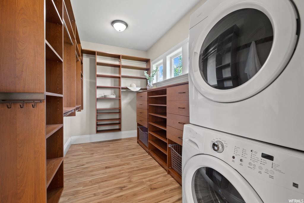 Laundry room with light hardwood floors and stacked washer and clothes dryer
