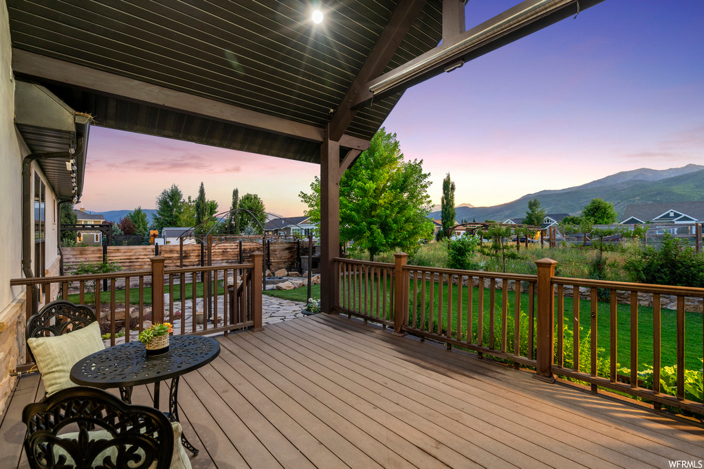 Deck at dusk featuring a mountain view and a yard