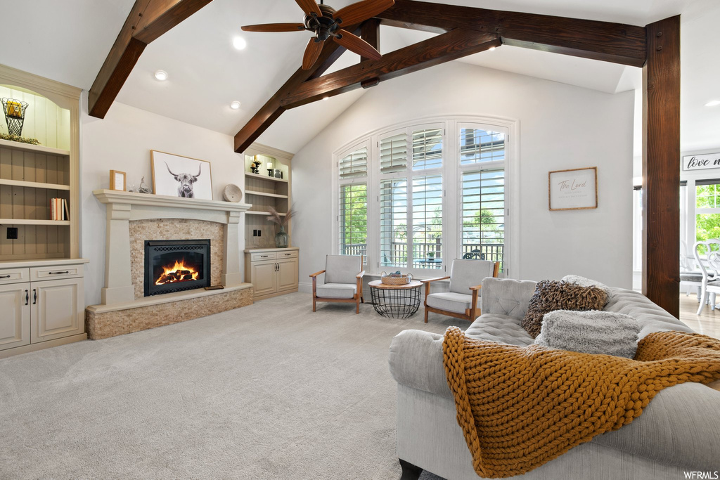 Carpeted living room featuring a fireplace, built in features, and vaulted ceiling with beams