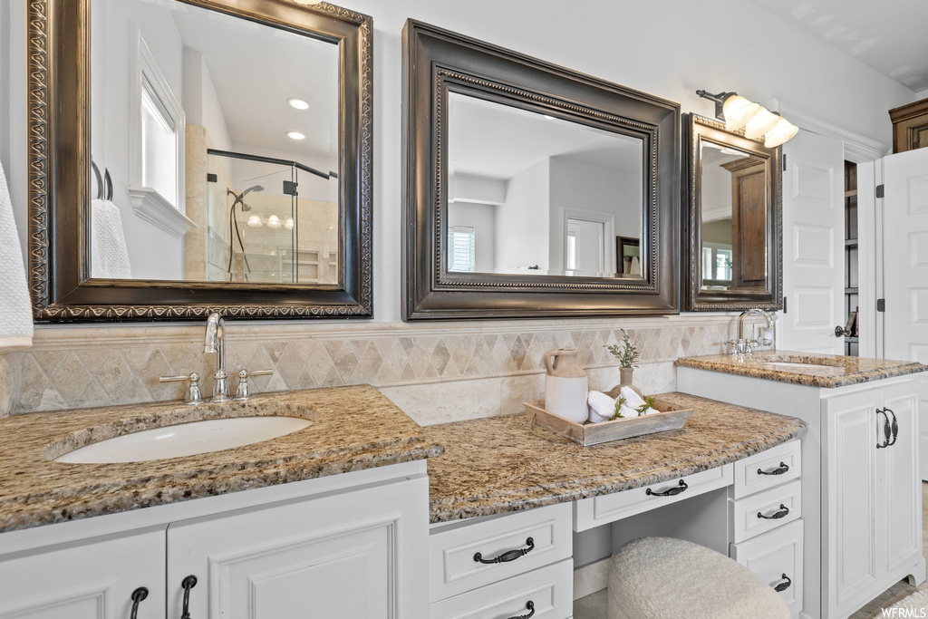 Bathroom featuring backsplash, dual large vanity, a shower, and mirror