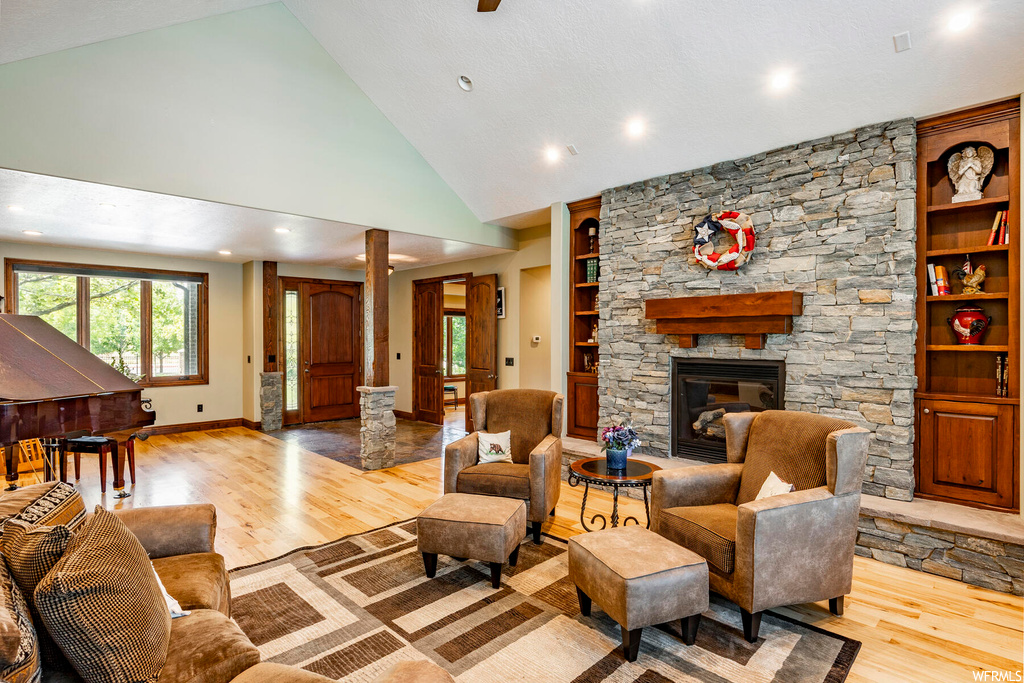 Hardwood floored living room with a fireplace, vaulted ceiling, and a high ceiling