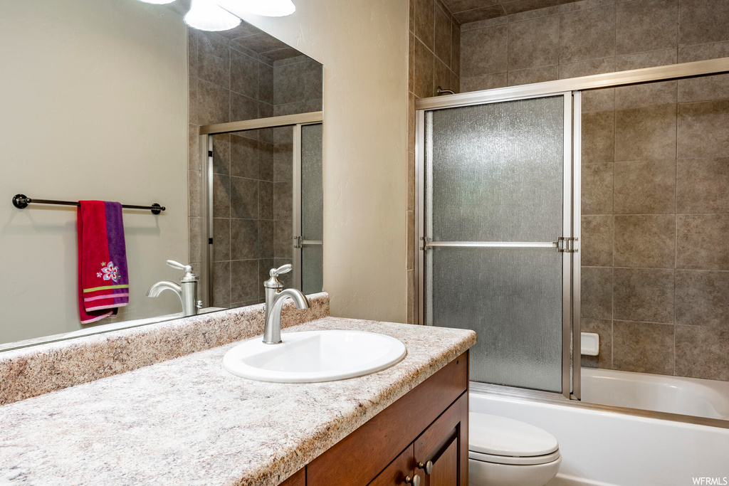 Full bathroom with vanity, bath / shower combo with glass door, and mirror