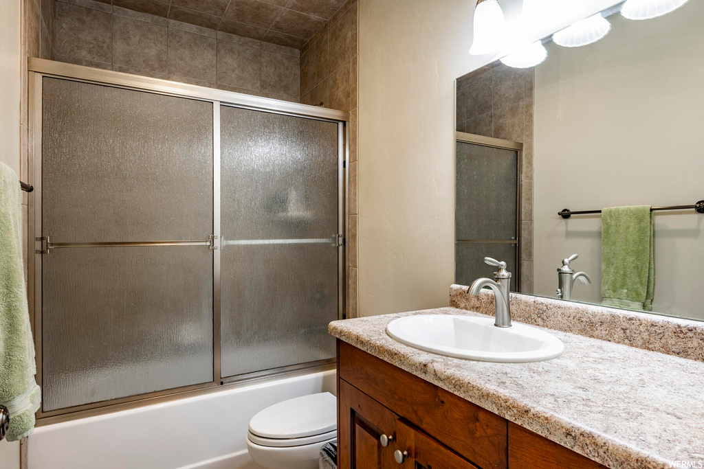 Full bathroom featuring shower / bath combination with glass door, vanity with extensive cabinet space, and mirror
