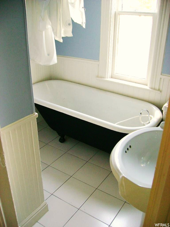Bathroom with light tile floors and a tub