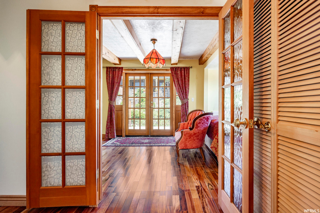 Entryway with beamed ceiling, light hardwood floors, and french doors