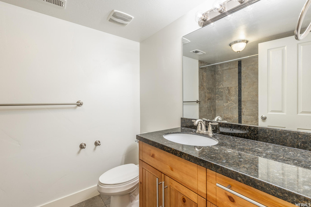 Bathroom with vanity with extensive cabinet space, tile floors, and mirror