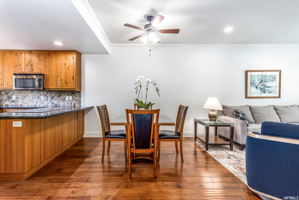Wood floored dining area with crown molding and ceiling fan