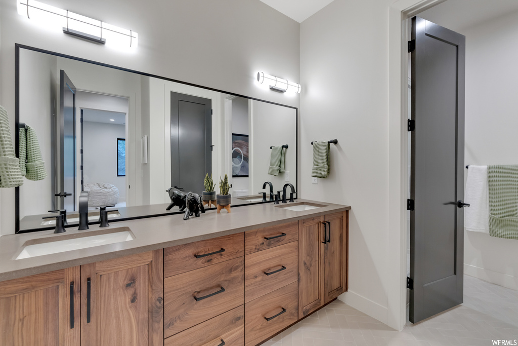 Bathroom featuring light tile floors, mirror, and dual large bowl vanity