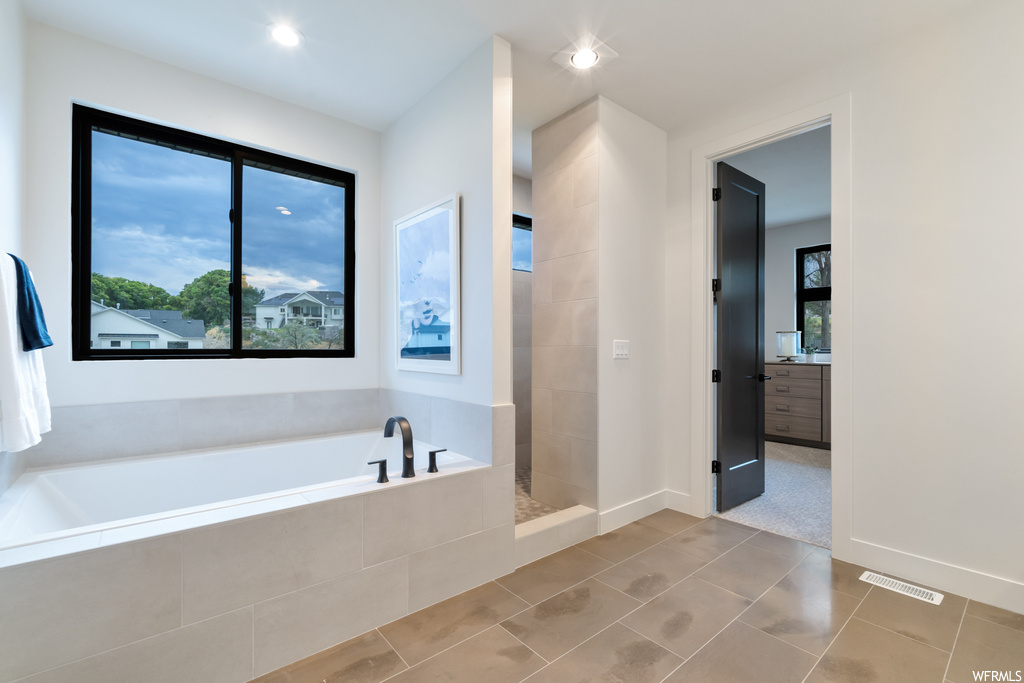 Bathroom featuring tiled tub and light tile flooring