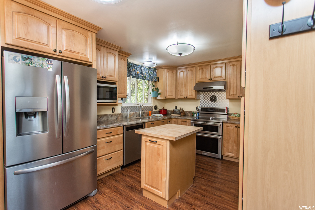 Kitchen featuring backsplash, dark hardwood floors, stainless steel appliances, and brown cabinets
