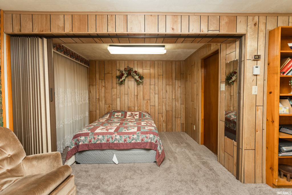 Bedroom featuring light carpet and wooden walls