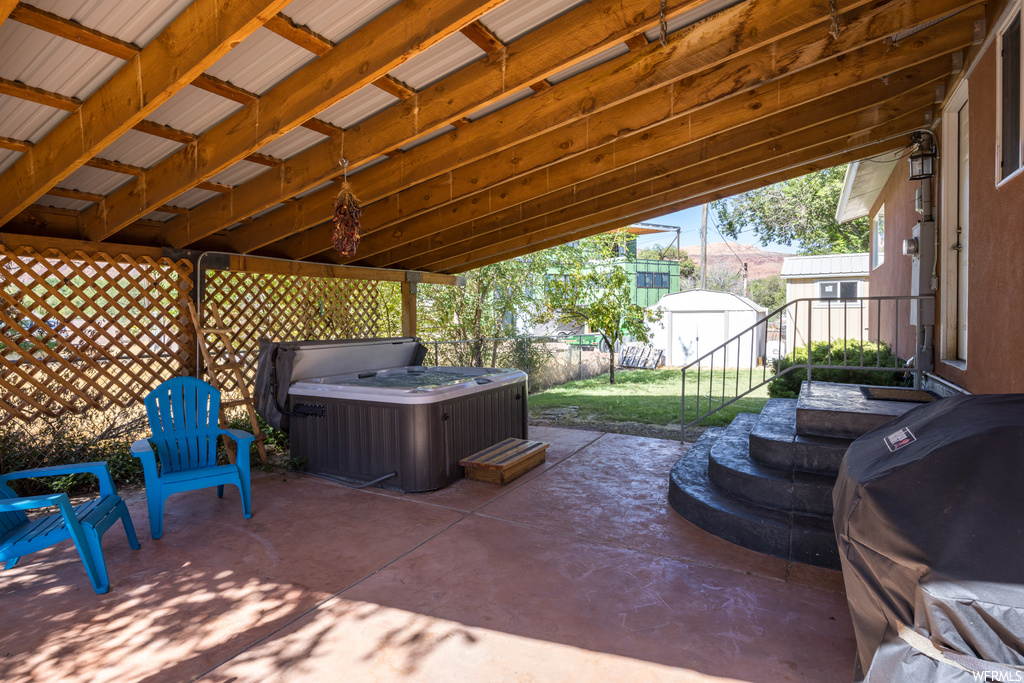 View of patio featuring hot tub and a shed