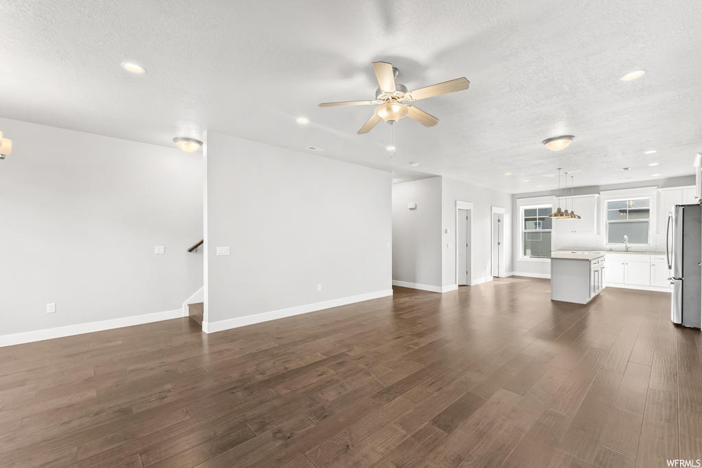 Living room with ceiling fan, a textured ceiling, and light hardwood floors