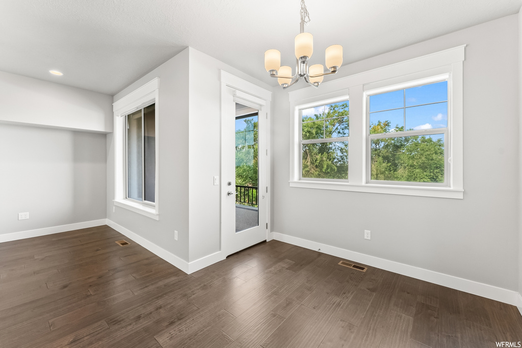 Hardwood floored empty room featuring a wealth of natural light
