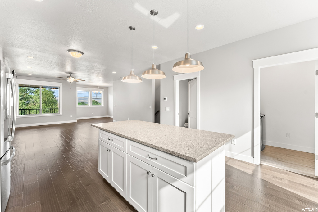 Kitchen with pendant lighting, white cabinets, hardwood flooring, and ceiling fan